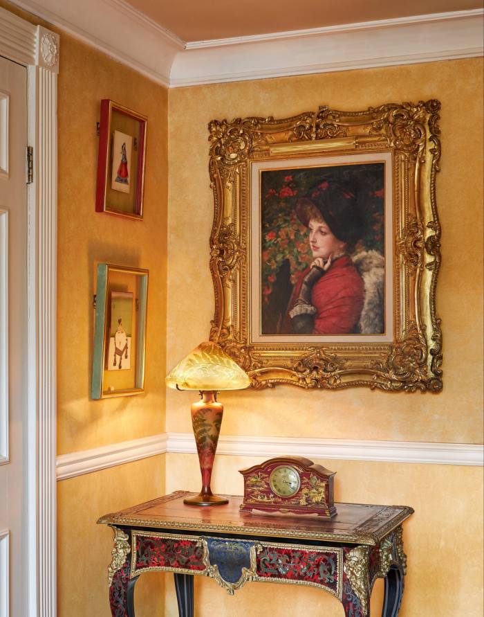 A portrait of a woman in a gilt frame on a hallway wall