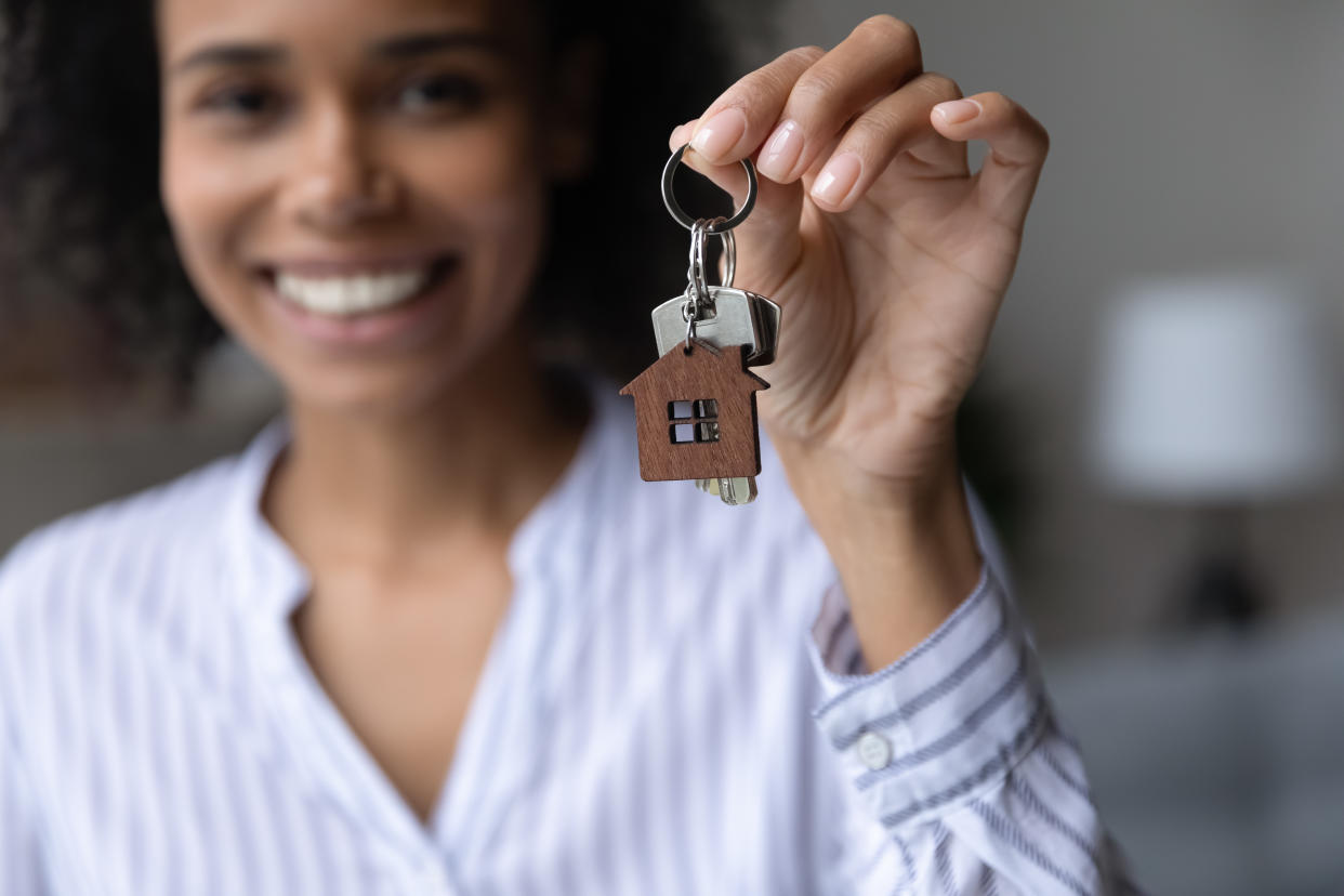 Close up focus on keys in happy African American woman hand, smiling satisfied young female tenant homeowner excited by relocation, purchasing first own apartment home, ownership and safety concept