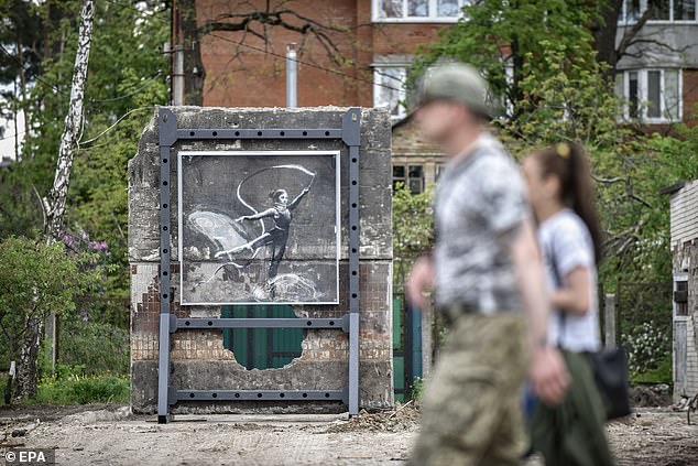 People walk past a mural by British street artist Banksy installed for viewing at a new location after it was removed from a damaged building set to be demolished, in Irpin, outskirts of Kyiv (Kiev), Ukraine, on May 13, 2023