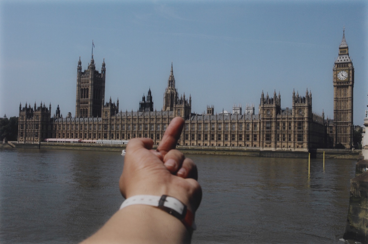 A photograph of a hand giving the middle finger to Westminster Abbey in London.