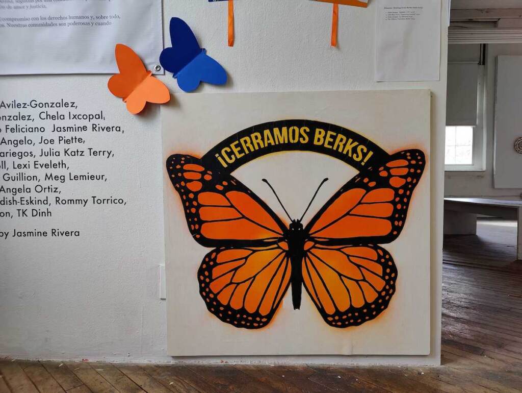 A sign reads ¡Cerramos Berks! and depicts a large monarch butterfly.
