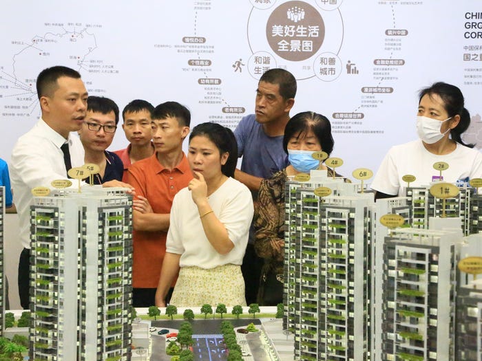 Local residents look at a model of a Poly Real Estate Group housing project at a real estate showroom on May 25, 2023 in Sanya, Hainan Province of China.