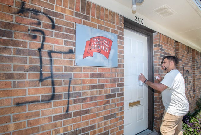 Honor Bell III spray paints over Nazi symbols painted on the Pensacola Liberation Center on West Yonge Street in Pensacola on Friday, Aug. 4, 2023. The overnight graffiti is the latest anti-Semitic vandalism in the Pensacola area.