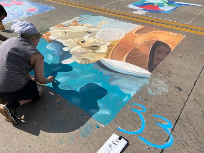 An artist works on their artwork on Washington Street at the 2022 edition of MidWest One's Rock the Chalk.