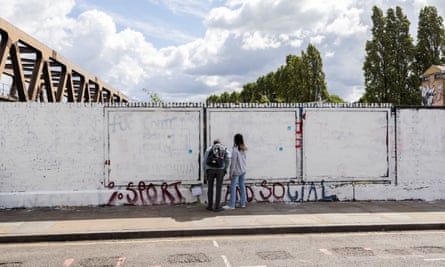 Two people by white wall with small amount of graffiti.