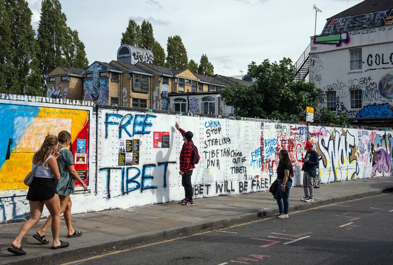 A man sprays a pro-democracy message on a wall that had been graffitied with Chinese Communist Party ideology, on Monday, Aug. 7, 2023 in Brick Lane, London, England. Credit: Carl Court/Getty Images