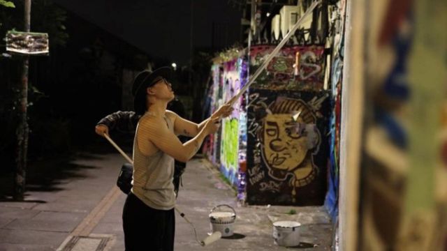 The overseas Chinese Royal Art College student whitewashing out existing graffiti and readying it for his version of graffiti with Chinese characteristics.
