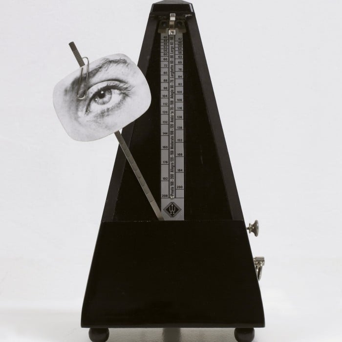 A black metronome with a black-and-white image of an eye on its pendulum