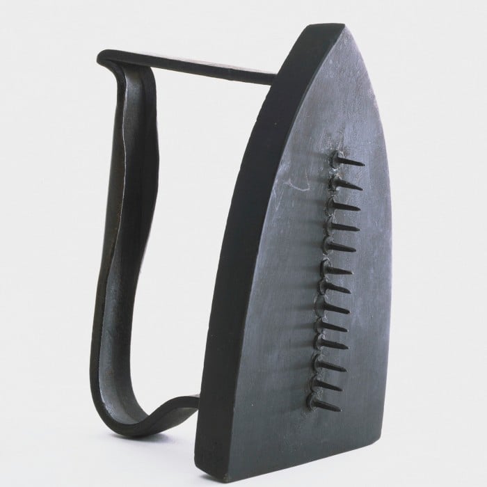 An iron, painted black, with row of 13 nails, heads glued to its underside