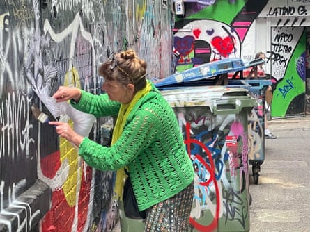 Street artist Deborah Wood stencils a wall.