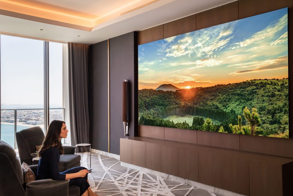 woman holding remote control for Samsung The Wall in hotel suite