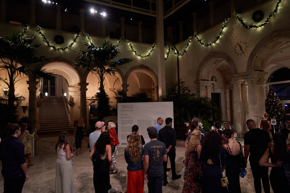 A group of party guests beneath a columned structure bedecked with holiday lights.