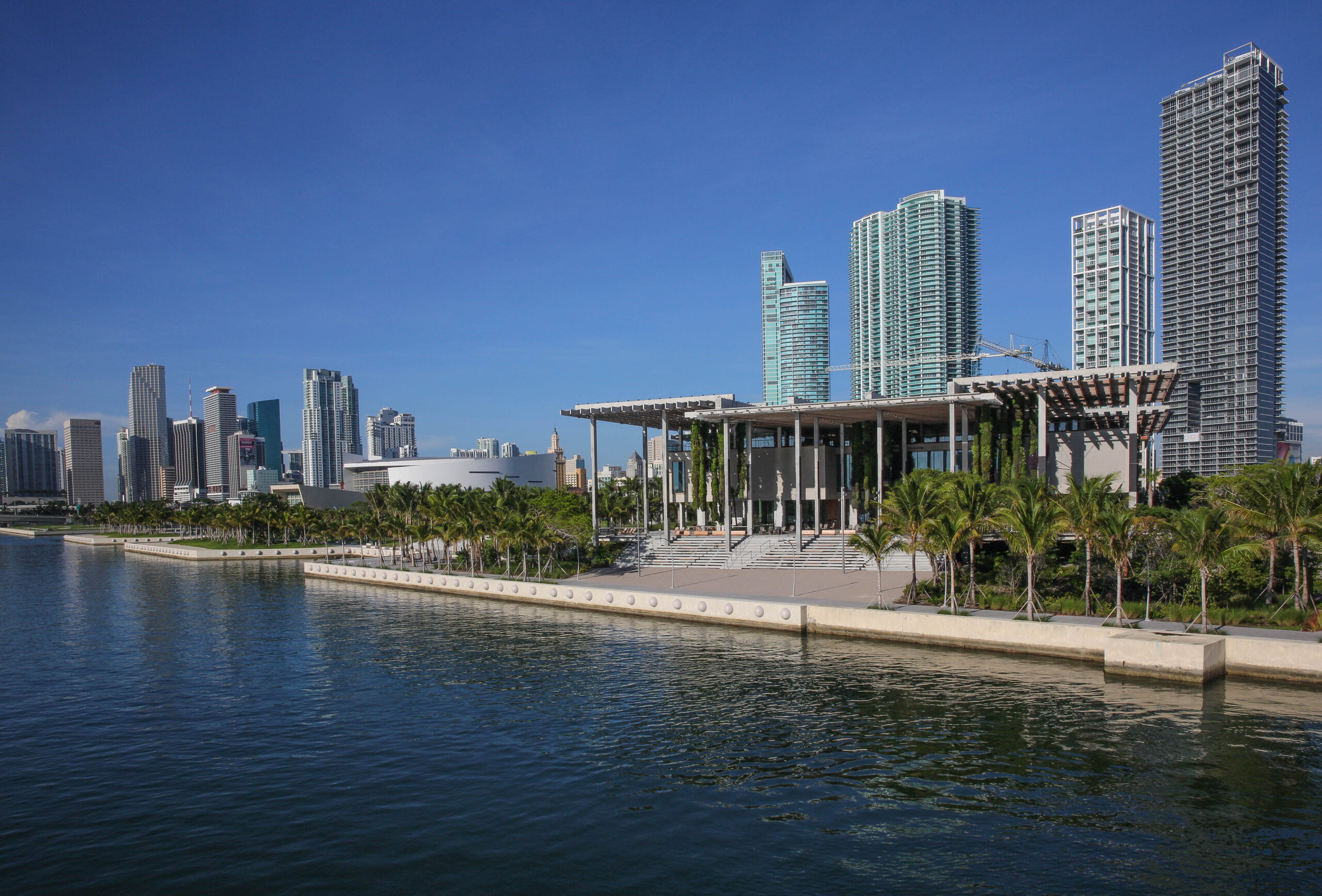 A building in front of water and several skyscrapers.