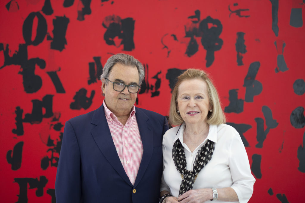Portrait of Rosa and Carlos de la Cruz with one of their recent acquisitions, Glenn Ligon Debris Field (Red) # 3 (2018). Courtesy of the de la Cruz Collection.