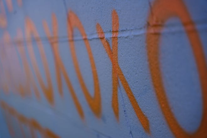 A row of orange doodle marks sit Thursday, May 2, 2024, on a wall Indianapolis street artist Michael 'Kwazar' Martin has dedicated to current Indiana sports figures. In the coming weeks he will be painting his final subject on the wall, Indianapolis Colts quarterback Anthony Richardson.