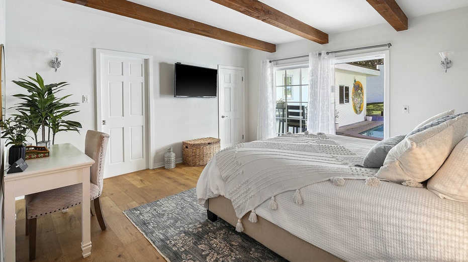 bedroom with dark wood beams on the ceiling and a TV against the wall